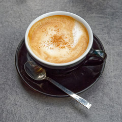 hot Italian cappuccino black cup on grey table background