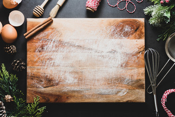 Christmas cooking or menu mock up. Empty cutting board and kitchen utensiles on dark background. Top view. Copy space.