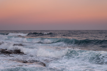Fototapeta na wymiar olas en una puesta de sol rosada 2
