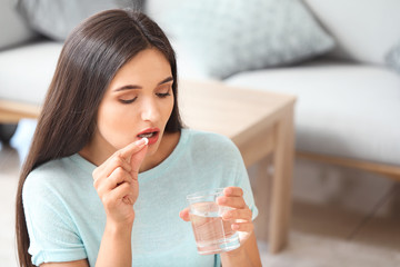 Young woman taking medicine at home