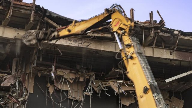 Destruction of the cinema building on a steel frame with a machine with hydraulic scissors, time lapse