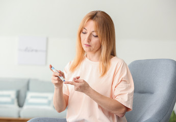 Diabetic woman taking blood sample with lancet pen at home