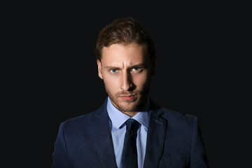Portrait of handsome angry businessman on dark background