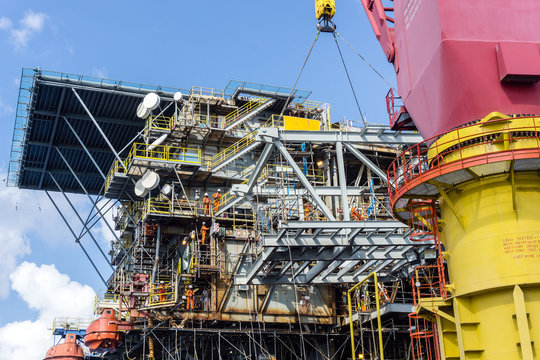 Offshore Crane On Board A Construction Work Barge Performing Heavy Lifting Of A Frame Strcuture From A Work Barge At Oil Field