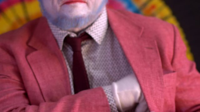 elderly mime man in large glasses with blue hair and beard in bright pink jacket and tie in white gloves. clown takes out pack of money from his pocket, recounts it and puts it back. Happy clown