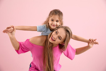 Happy woman and her little daughter on color background