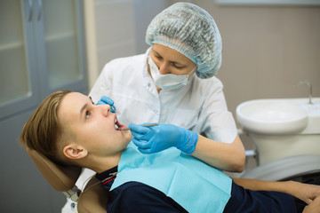 Patient sitting in a dentist chair on examination in dental room.