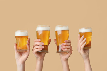 Hands with glasses of beer on color background