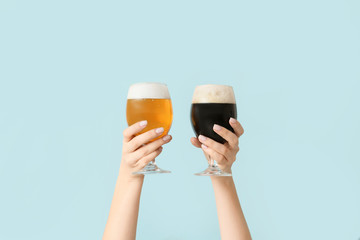 Hands with glasses of beer on color background