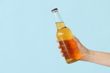 Hand with bottle of beer on color background