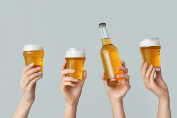 Hands with fresh beer on grey background