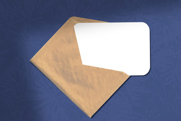 Envelope with a sheet of paper on a blue background. Layout with texture overlay Christmas tree. Natural light casts a shadow from the window opening.