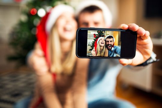 Couple using phone to make selfie at Christmas time