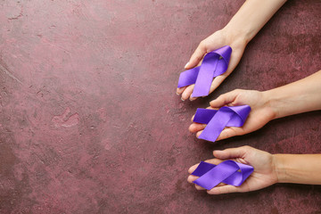 Obraz na płótnie Canvas Female hands with purple ribbons as symbol of World Cancer Day on color background