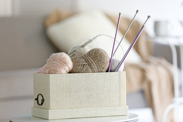 Box with knitting yarns on table
