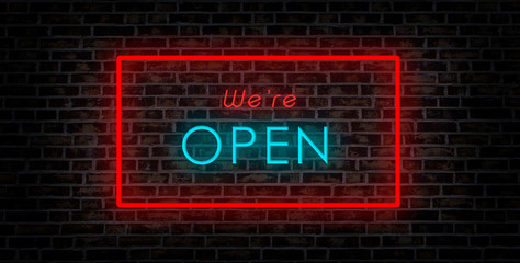 we are open sign. neon illuminated blue and red font on brick wall.