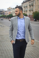 Portrait of a businessman on the street near the road of a European city. A bearded handsome man dressed stylishly. Fashionable guy hipster. Stock photos