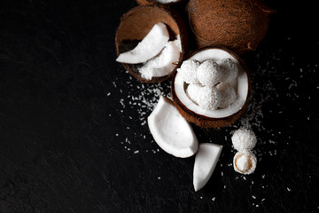 cooked coconut milk candies on a black dark background, ingredients for a dessert with coconuts, a sweet product with coconut flakes
