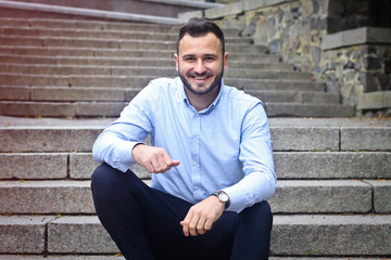 Fototapeta premium Portrait of a bearded man near the big steps of an old European castle. Businessman thinking over a future project. Fashionable guy with stylish clothes.