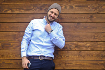 Fototapeta premium Portrait of a handsome man in a shirt on a wooden wall background. Businessman in stylish clothes. Stock Photo for design
