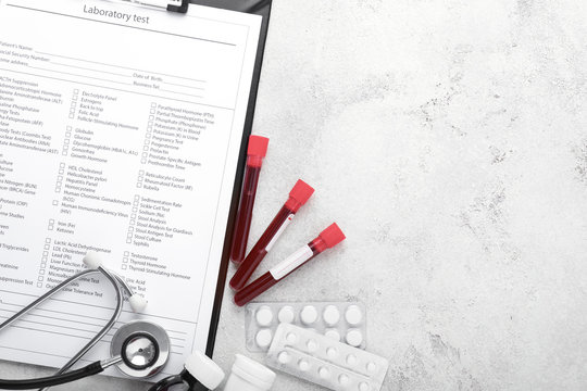 Laboratory test form, stethoscope, pills and blood samples on table
