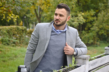 Portrait of a sexy man dressed in a suit. Fashionable guy in the autumn nature near a white wooden fence. Businessman relaxes. Skok photo for design © snb2087