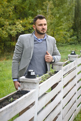 Portrait of a sexy man dressed in a suit. Fashionable guy in the autumn nature near a white wooden fence. Businessman relaxes. Skok photo for design © snb2087