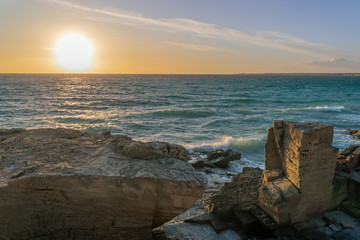 Mediterranean landscape in Ses Covetes, Mallorca. Strange rock formations, and a huge and spectacular sun setting on the maritime horizon.