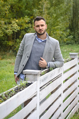 Portrait of a sexy man dressed in a suit. Fashionable guy in the autumn nature near a white wooden fence. Businessman relaxes. Skok photo for design © snb2087