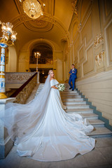Obraz na płótnie Canvas Beautiful wedding couple walking a gorgeous stairs holding hands and looks to each other. In opera