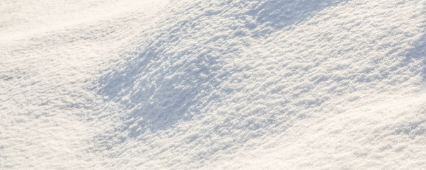 Hilly surface covered with fresh snow in the garden on a sunny day. Natural winter background.
