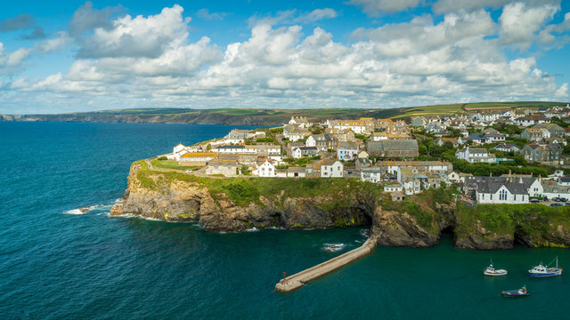 Scenic view of Port Isaac, a coastal town in Cornwall, England. Rocky rugged coast with slate, meadows and coastal paths. Turqoise water with fishing boats.
