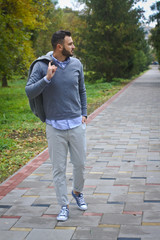 Young sexy guy strolling through the autumn, summer park. man drinking coffee, tea in the nature. European countryside. Stock Photo for design