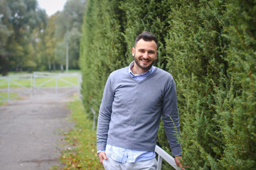 Young guy on the background of European, American city. man in the background of trees and fields and fence. The owner of a beautiful land for business