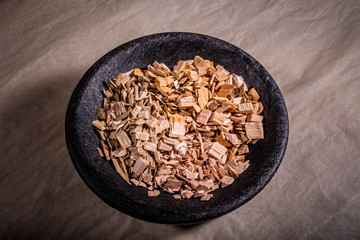 Sawdust for smoking meat in a black bowl. On the paper