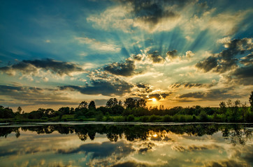 Watching a sunny sunset on the lake, clouds reflected on the water