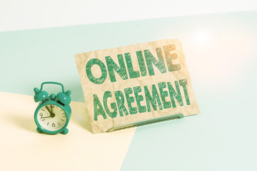 Text sign showing Online Agreement. Business photo text contract modelled signed and executed electronically Mini size alarm clock beside a Paper sheet placed tilted on pastel backdrop