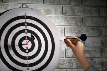 Young woman playing darts indoors