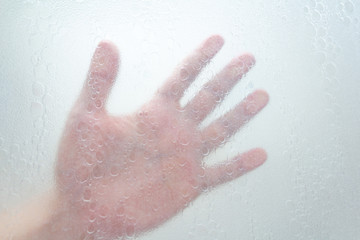 Fototapeta premium hand through a shower screen with drops on a light background