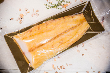White smoked fish in a sealed vacuum package on the background of chips for smoking