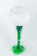 Fototapeta na wymiar wine glass with a green leg with splashes of water on a white background