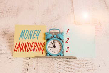 Conceptual hand writing showing Money Laundering. Concept meaning concealment of the origins of illegally obtained money Mini blue clock standing above buffer wire between two paper