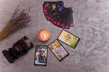 Divination cards alignment with black Buddha statue, money banknotes and candles. Mystery,...