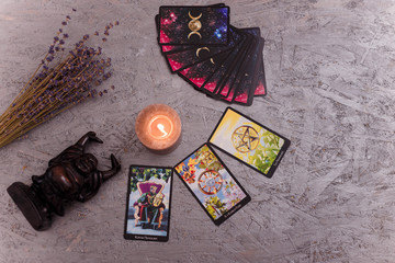 Divination cards alignment with black Buddha statue, money banknotes and candles. Mystery, astrology, fortune telling, belief, prosperity and wealth concept.