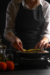 Japanese or Oriental cuisine, Seafood, Chef cooks fish, frying in a pan. with ingredients on the table. Healthy and healthy food, sale of seafood, fish shops. Vertical frame.