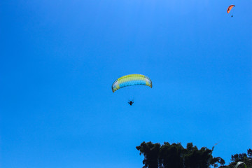 paraglider flying in blue sky on valleys landscape in Indonesia