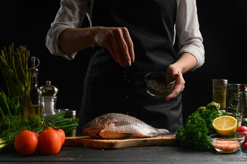 Chef cooks fish on a background with ingredients for cooking fish. Freezing in motion, Sale of fish...