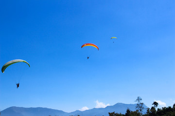 paraglider flying in blue sky on valleys landscape in Indonesia