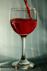 Red juice being poured on a wine glass with bubbles