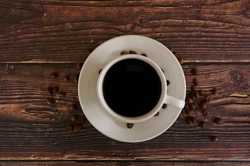 cup of coffee with beans on wooden table